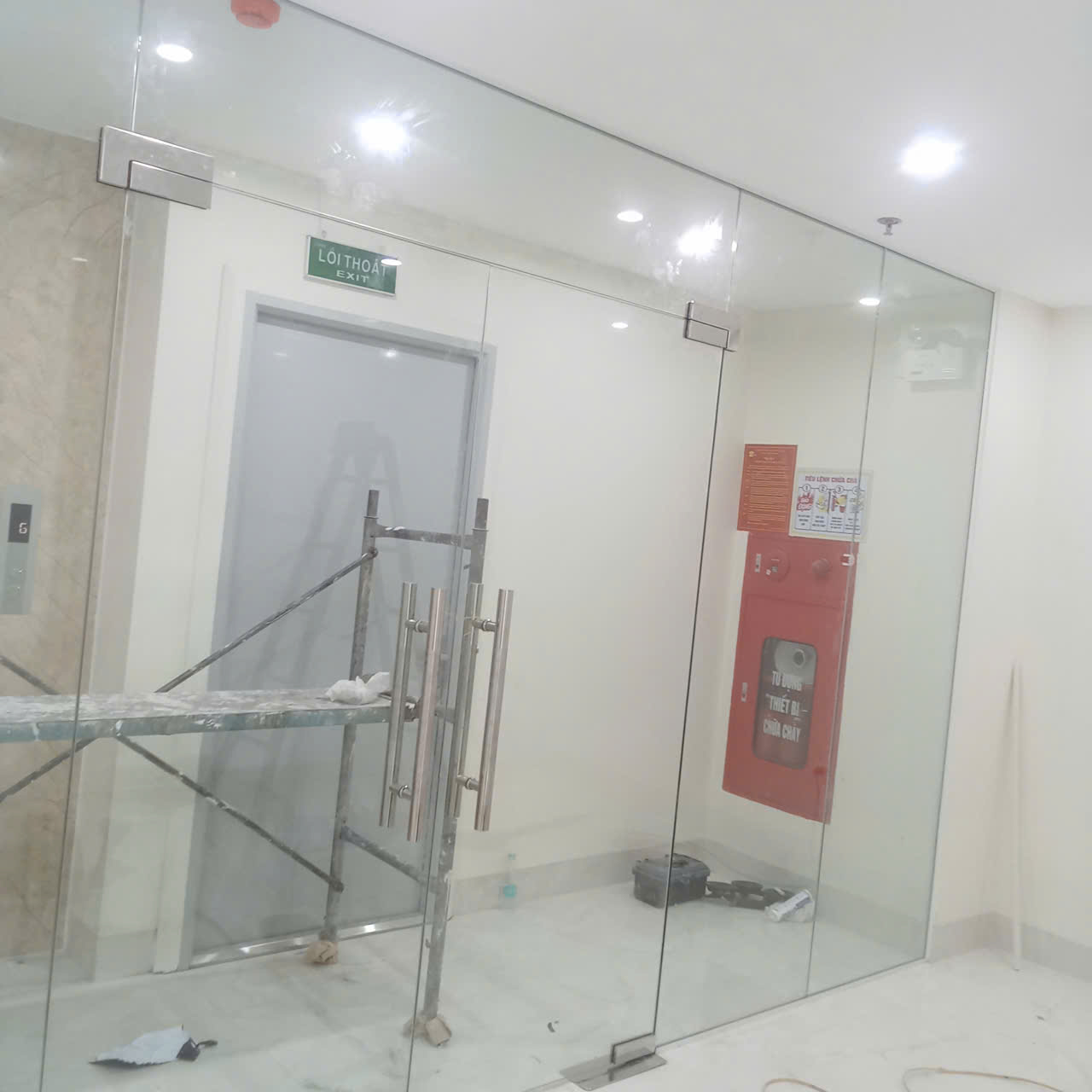 Cửa kính cường lực văn phòng với tay nắm inox đôi đang trong quá trình thi công lắp đặt