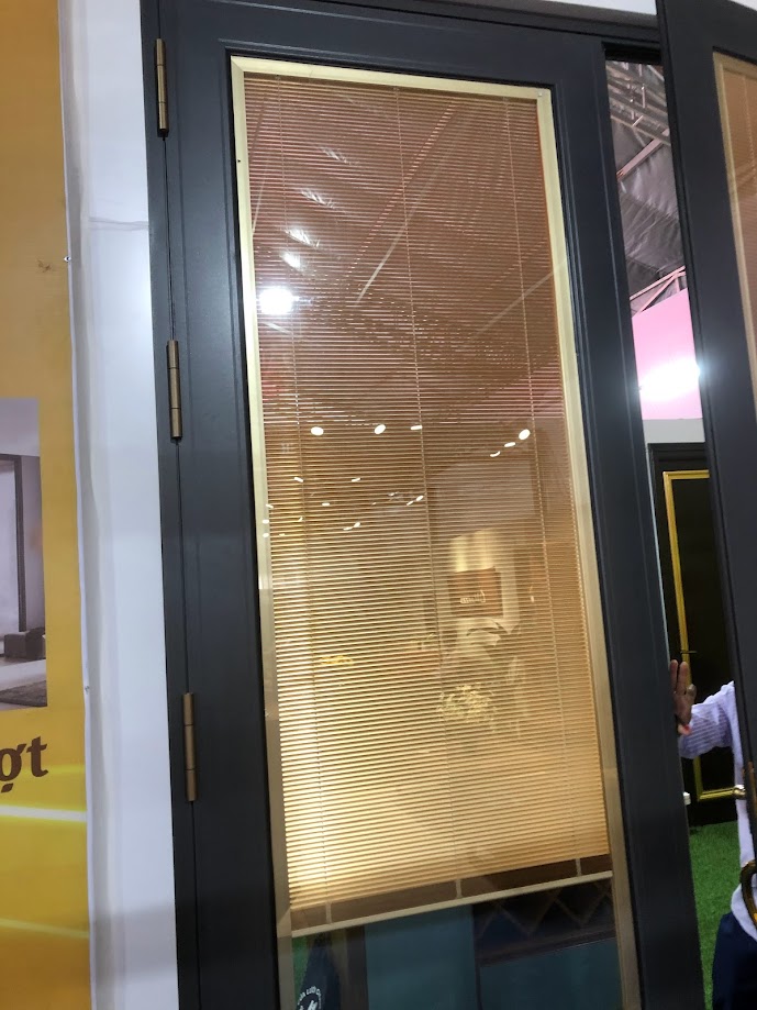 Black aluminum-framed glass doors with integrated blinds are on display in the showroom.