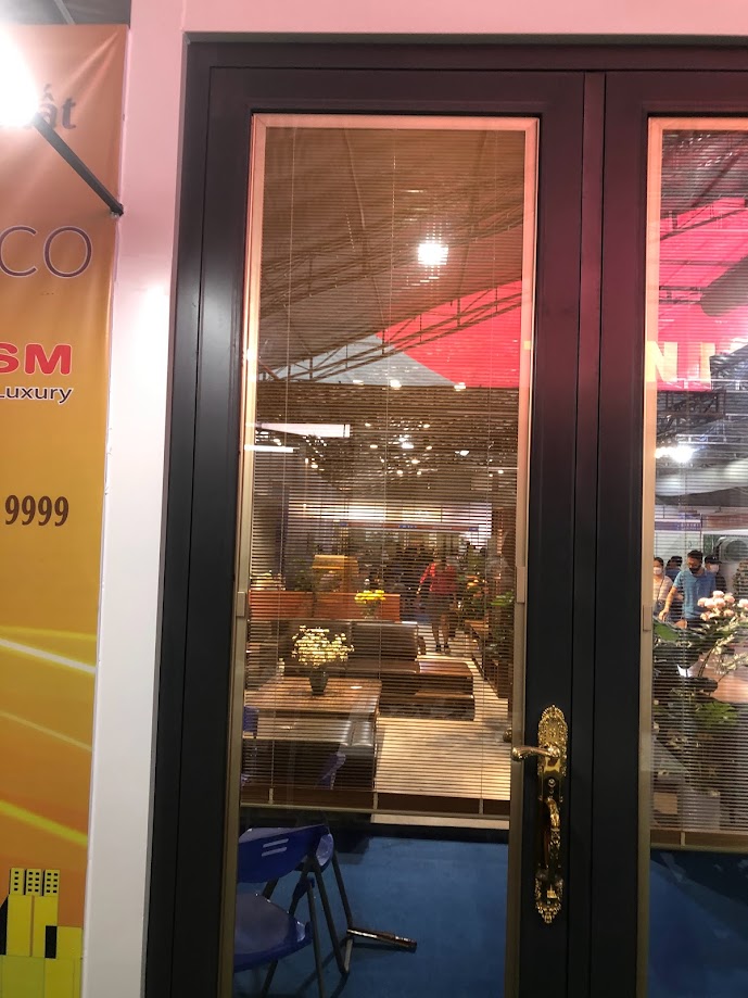High-end aluminum-framed glass doors with blinds and gold-plated handles offer a view into the furniture showroom.