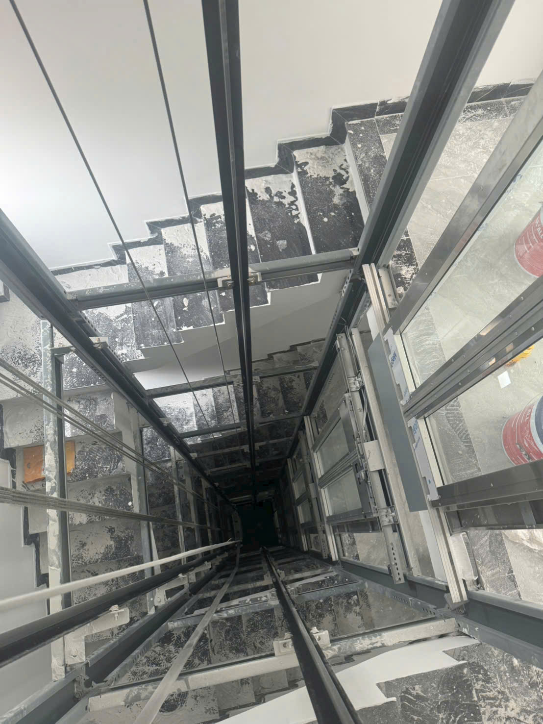 A top-down view of a home elevator shaft under construction; the guide rails and elevator shaft are not yet complete.