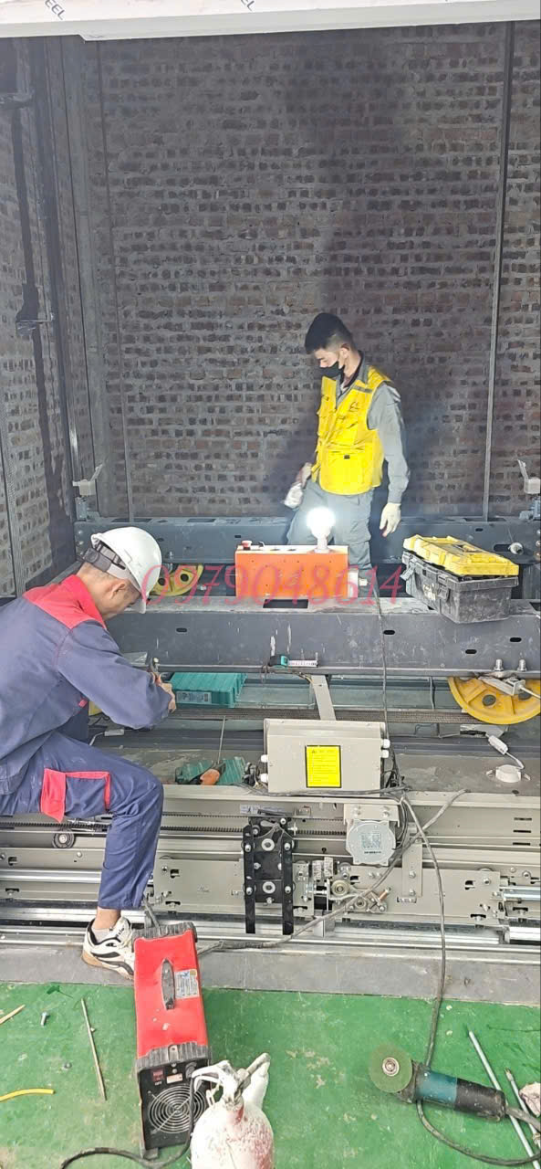 Technicians are installing the elevator door traction system in the brick elevator shaft.