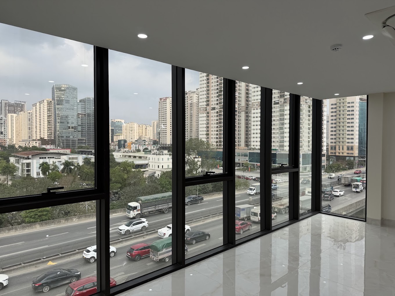 Vách kính khung tối màu trong văn phòng nhìn ra khu đô thị