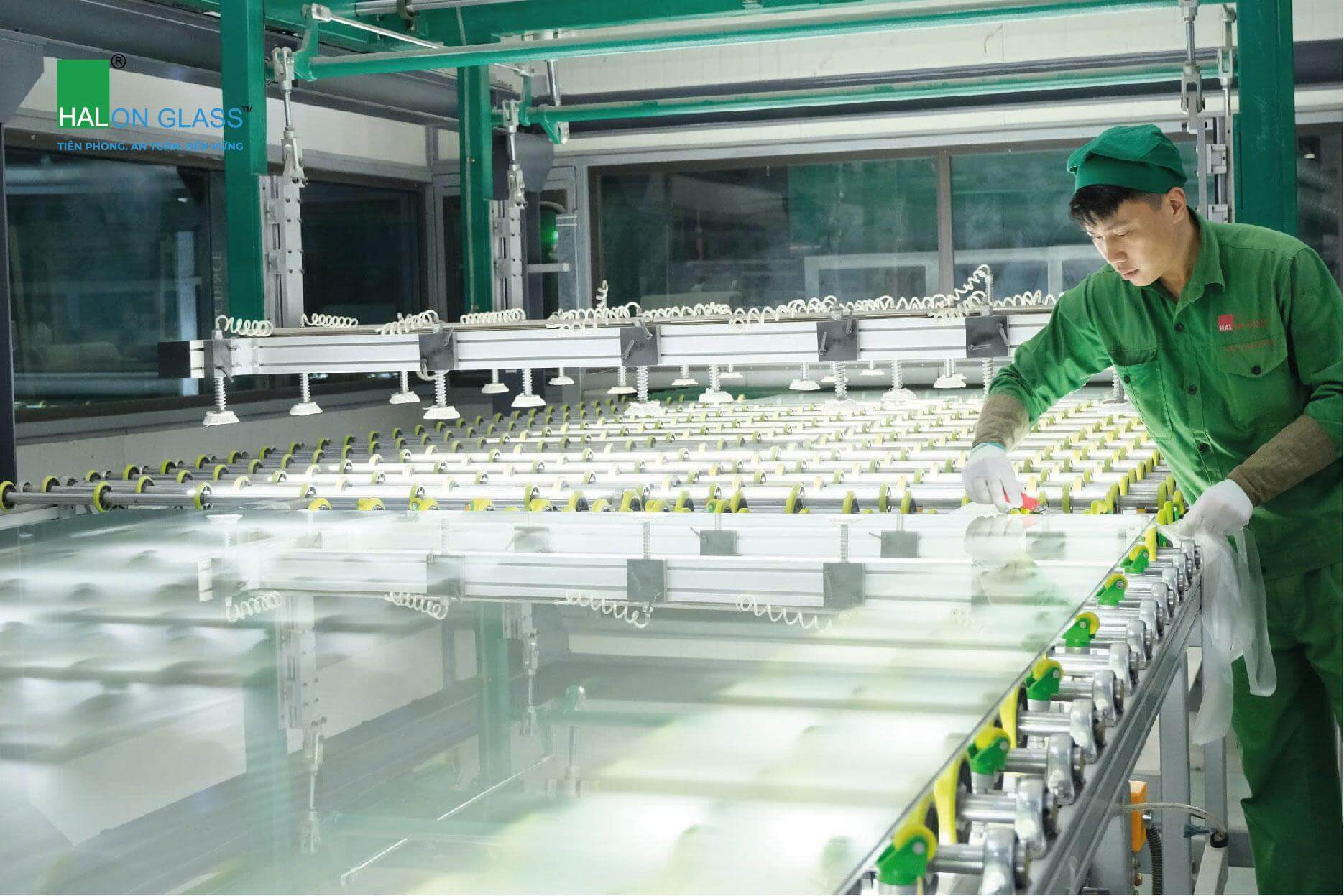 Nhân viên thao tác với tấm kính trên dây chuyền trong khu vực sản xuất